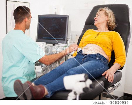 Man sonographer examining female patient Man sonographer examining female patient 56630952