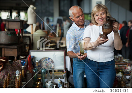 Smiling mature spouses buying retro handicrafts on flea market Smiling mature spouses buying retro handicrafts on flea market 56631452