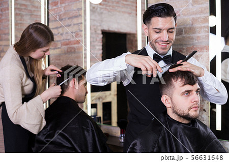Male hairdresser cutting hair of male client 56631648