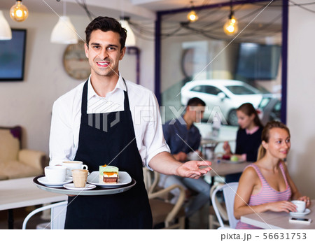 Waiter holding served tray meeting visitors at pastry bar Waiter holding served tray meeting visitors at pastry bar 56631753