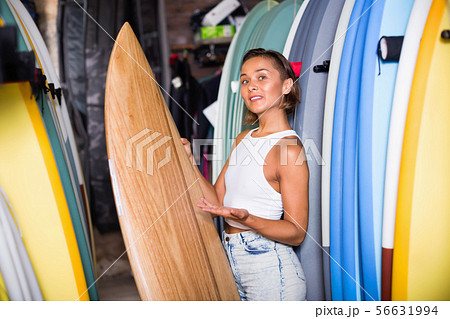 Portrait of smiling woman with board for surfing in the shop 56631994