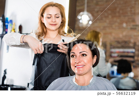 Hairdresser does to woman haircut with use of scissors and hairbrushes Hairdresser does to woman haircut with use of scissors and hairbrushes 56632119