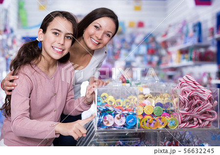Woman with smiling girl choosing candies in shop Woman with smiling girl choosing candies in shop 56632245