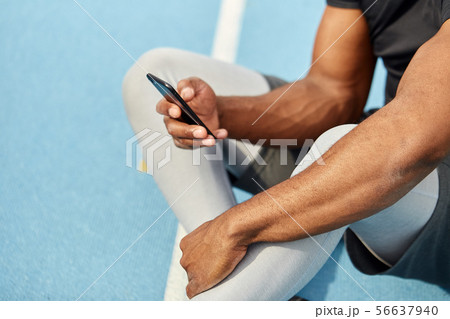 well-built muscular runner holding smart phone, surfing, browsing the net 56637940