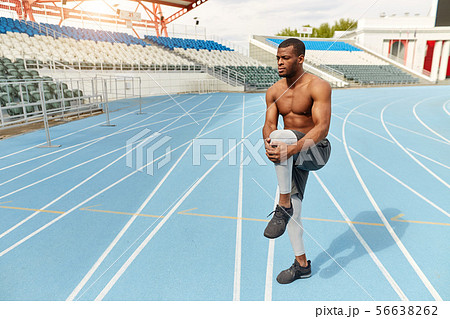 motivated strong runner stretching leg in the stadium 56638262