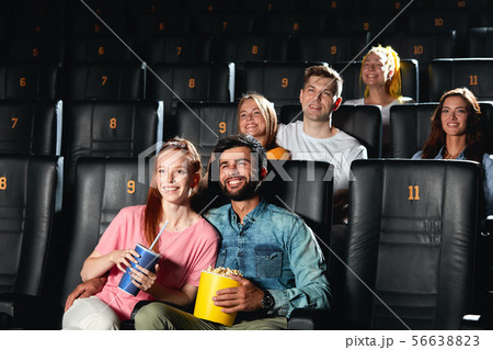 Cheerful good looking company enjoying premiere and eating popcorn. Cheerful good looking company enjoying premiere and eating popcorn. 56638823