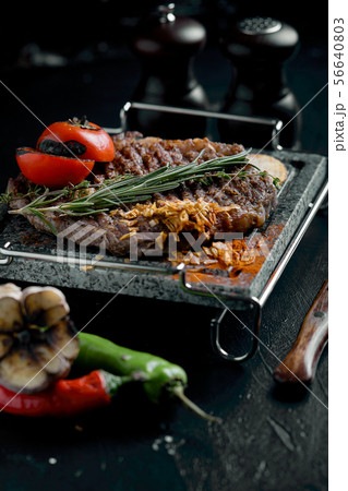 Grilled steak with knife and fork carved on black stone slate. Steak on a hot marble stone. Copy 56640803