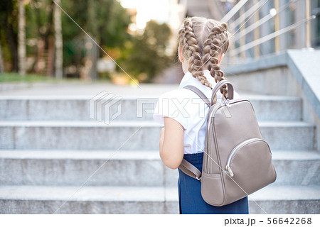 Girl with blond hair rejoices in returning to school from behind. 56642268