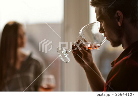Young beautiful couple in plaid shirts on the balcony of a multistory building. Drink and taste wine 56644107
