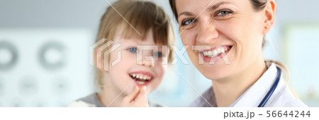 Smiling cute little patient interacting with female doctor Smiling cute little patient interacting with female doctor 56644244