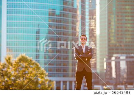 Businessman looking on copy space while standing against glass skyscraper Businessman looking on copy space while standing against glass skyscraper 56645493