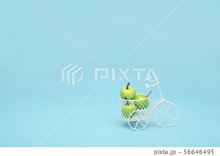 White wire bicycle with a basket filled with mini fruit. Near the bucket with vegetables and fruits 56646495