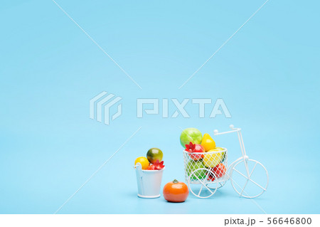 White wire bicycle with a basket filled with mini fruit. Near the bucket with vegetables and fruits 56646800