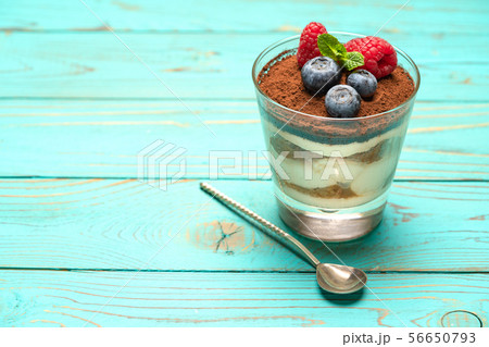 Classic tiramisu dessert with blueberries and strawberries in a glass cup on wooden background 56650793