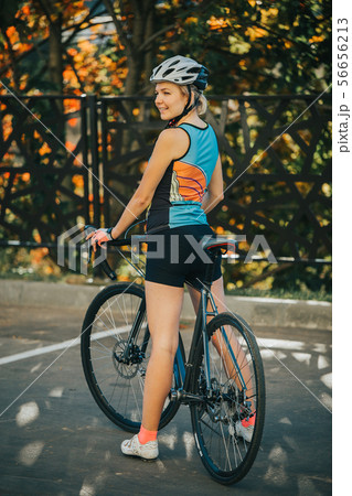Photo on side of young woman in helmet on bike ride on summer day 56656213