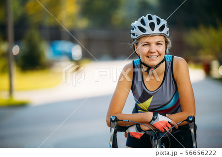 Image of young woman in helmet on bike ride on summer day 56656222