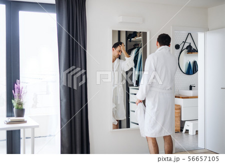 Young man looking in mirror in bedroom in the morning, daily routine. Young man looking in mirror in bedroom in the morning, daily routine. 56657105