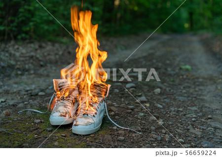 Used white high sneakers burning on a rural road 56659224