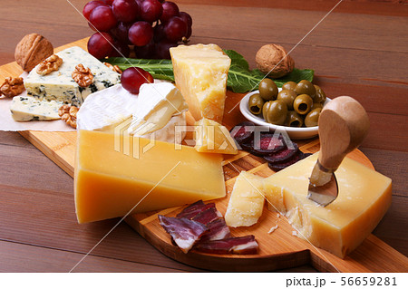 Assortment of cheese with fruits, grapes, nuts and cheese knife on a wooden serving tray. 56659281