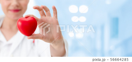 Doctor holding a red heart at hospital office. 56664285