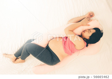 Happy pregnant woman sleeping on bed in bedroom. Happy pregnant woman sleeping on bed in bedroom. 56665462