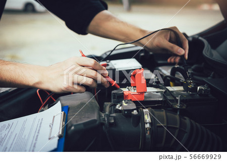 Car mechanic is using the car battery meter to Car mechanic is using the car battery meter to 56669929