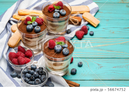 Classic tiramisu dessert with blueberries and strawberries in a glass cup and savoiardi cookies on 56674752