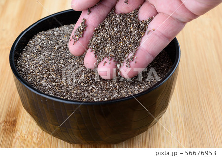 Chia seeds sprinkle from a human palm into a bowl. Chia seeds sprinkle from a human palm into a bowl. 56676953