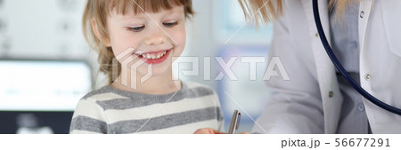 Female doctor listening cute little patient and writing registration information on clipboard pad 56677291