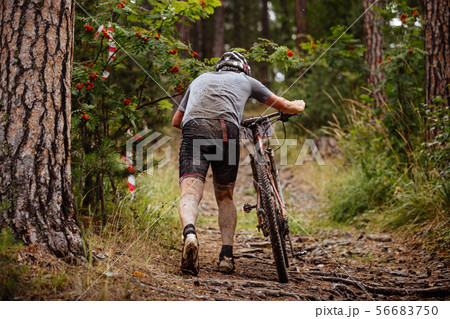 dirty and tired cyclist walking uphill dirty and tired cyclist walking uphill 56683750