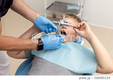 Little boy lays on chair while dentist fixing up orthodontic arch 56690320