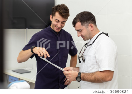 Two stomatologiests talking about results of x-ray of their patient's jaw 56690324
