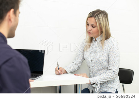 Blond adult woman signing up contract in hospital on buisness meeting. Selective focus Blond adult woman signing up contract in hospital on buisness meeting. Selective focus 56690524