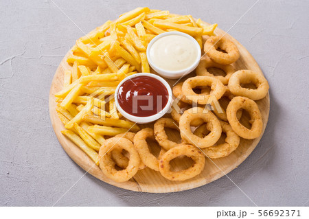 French fries and onion rings with sauces 56692371