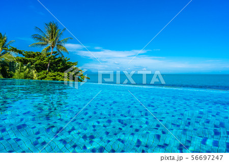 Beautiful luxury outdoor swimming pool in hotel resort with sea ocean around coconut palm tree and white cloud on blue sky 56697247