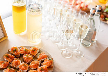 the buffet at the reception. Glasses of wine and champagne. Assortment of canapes on wooden board 56702833