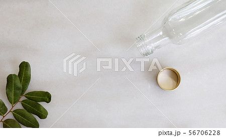 Flat lay of a long empty glass bottle and leaves. Flat lay of a long empty glass bottle and leaves. 56706228
