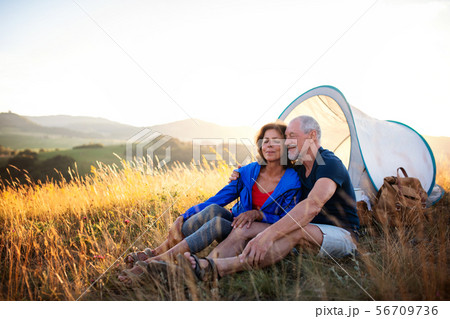 Senior tourist couple in love sitting in nature at sunset, resting. Senior tourist couple in love sitting in nature at sunset, resting. 56709736