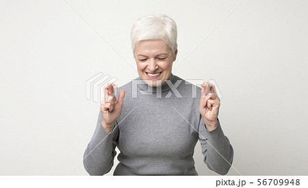 Optimistic senior woman crossing fingers with hope with closed eyes 56709948