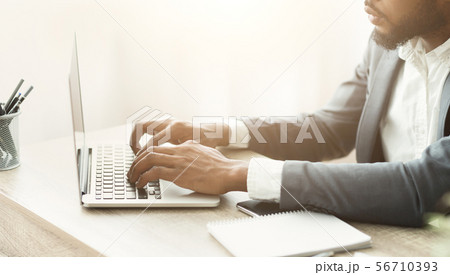 African american businessman typing on laptop filling financial reports African american businessman typing on laptop filling financial reports 56710393