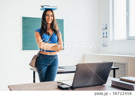Portrait of female student holding book on her head 56712458