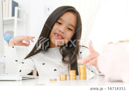 asian little girl playing with coins making stacks 56716351