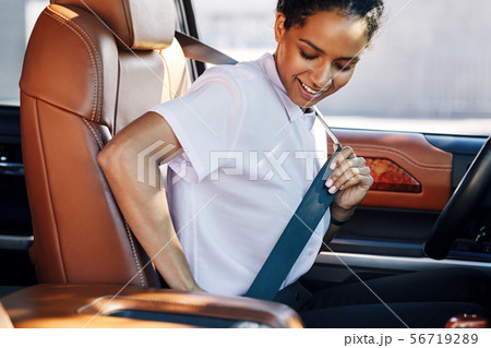 Young businesswoman fastening her seat belt Young businesswoman fastening her seat belt 56719289