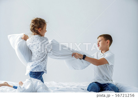Naughty twins girl and boy friendly fighting staged a pillow fight on the bed in the bedroom. Naughty twins girl and boy friendly fighting staged a pillow fight on the bed in the bedroom. 56721256