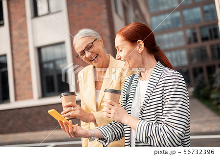 Two contented friends in stylish clothes laughing outdoors 56732396