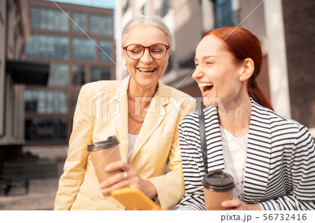 Businesswomen standing outdoors with paper cups of coffee Businesswomen standing outdoors with paper cups of coffee 56732416