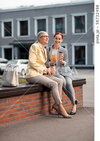 Two modern women sitting on the bench outdoors Two modern women sitting on the bench outdoors 56732498