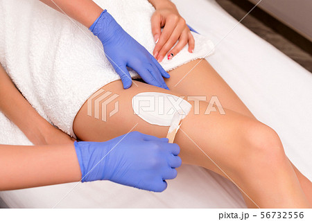 Beautician waxing female legs in spa center. Removing unnecessary hair on the legs. Procedure Beautician waxing female legs in spa center. Removing unnecessary hair on the legs. Procedure 56732556