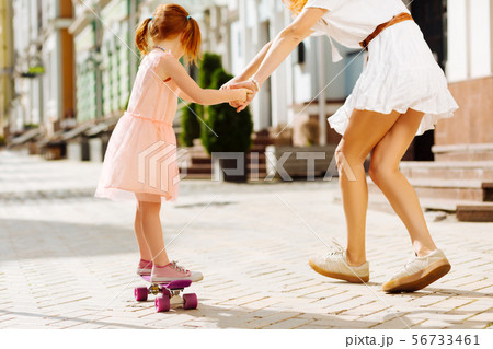 Active little girl going skateboarding with mom Active little girl going skateboarding with mom 56733461
