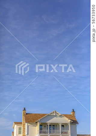 Upper storey of home againt sky with wispy clouds Upper storey of home againt sky with wispy clouds 56733950